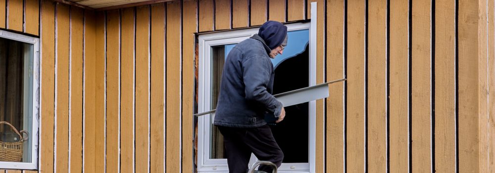 Exterior window finishing with metal jambs and mouldings, construction worker working standing on stepladder. Window Replacement and Siding Installation in Chicago by Midwest Windows